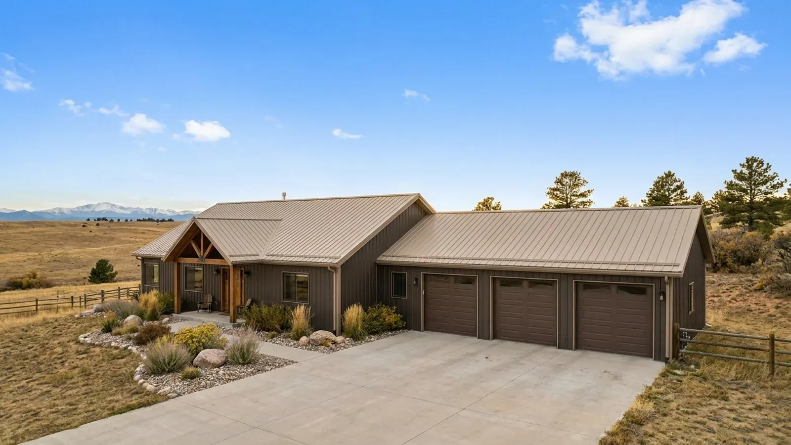 A barndominium home with an attached three-car garage wing and a concrete driveway leading to three residential garage doors.